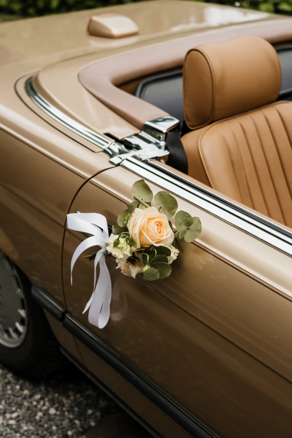 Oldtimer cabrio. Er hangt een bloemstuk aan de deur.